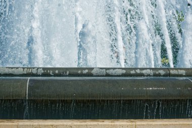 Çeşmeler yukarı doğru fışkırır ve beyaz köpüğe dönüşür. Beton bir kenardan dökülür. Su tabanında çağlayarak akıyor, yüzeyi parlak ve gürültülü yapıyor..