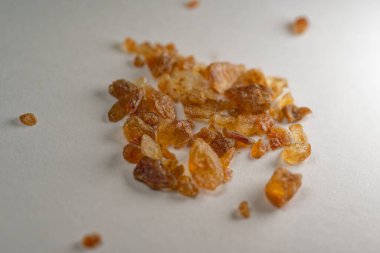 Beyaz yüzeydeki kahverengi kaya şekeri kristallerinin makro yakın görüntüsü. Doğal tatlandırıcı dokusu kahve, çay, fırın ve gıda malzemeleri için idealdir..