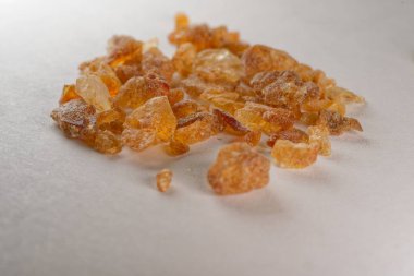 Beyaz yüzeydeki kahverengi kaya şekeri kristallerinin makro yakın görüntüsü. Doğal tatlandırıcı dokusu kahve, çay, fırın ve gıda malzemeleri için idealdir..