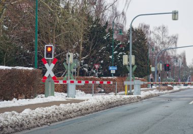 İndirilmiş bir bariyerle demiryolu geçidinde bir yol durdu. Bir haçın yanında küçük bir kırmızı ışık yanıyor, geçen bir treni beklemeleri için sürücüleri uyarıyorlar..