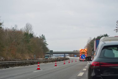 Otoban A7 E45 turuncu koni ve bir iş aracı sağ sapma okunu göstererek, trafiği açık güvenlik uyarılarıyla geçici bir çalışma alanına yönlendiriyor..