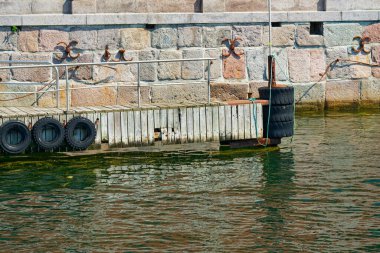 Küçük bir iskele kenetlenme teknelerini korumak için tampon görevi gören araba lastikleriyle kaplıdır. Taş levhalar ve ahşap bir rampa küçük gemiler için uygun bir iniş noktası olduğunu gösteriyor..