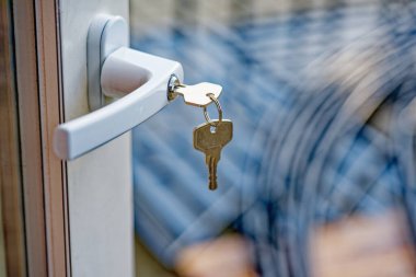 Beyaz kapı kolundan sarkan metal anahtarlar. Arka planı bulanık. Mavi ve beyaz desenli..