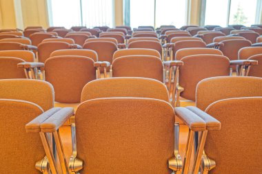 Boş kahverengi yastıklı sandalyeler geniş pencereli parlak bir odada, konferanslar, dersler veya toplantılar için uygun dizilmiş..