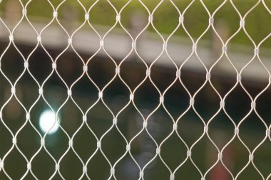 Beyaz güvenlik ağı, koruma ve güvenlik için kullanılan elmas desenli, bulanık arka plan, doğal renklere ve ışığa karşı.