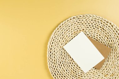 Kahverengi hasır masa paspası, sarı arka planda kurutulmuş palmiye yaprağı. Beyaz ve kahverengi kartlar, saman yuvarlak tepsi, düz döşeme, kopyalama alanı. 