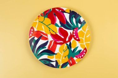 Sarı arkaplandaki renkli tabağın üst görüntüsü. Egzotik bitki plakası, yaz pikniği. Düz yat, boşluğu kopyala.