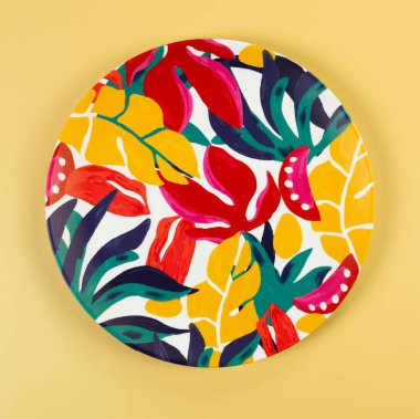 Sarı arkaplandaki renkli tabağın üst görüntüsü. Egzotik bitki plakası, yaz pikniği. Düz yat, boşluğu kopyala.