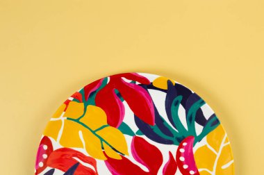 Sarı arkaplandaki renkli tabağın üst görüntüsü. Egzotik bitki plakası, yaz pikniği. Düz yat, boşluğu kopyala.