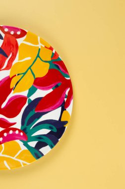 Sarı arkaplandaki renkli tabağın üst görüntüsü. Egzotik bitki plakası, yaz pikniği. Düz yat, boşluğu kopyala.