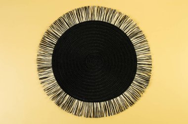 Sarı arkaplandaki siyah hasır masa örtüsünün üst görüntüsü. Saman yuvarlak tepsi, düz konum, kopyalama alanı. 