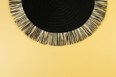 Sarı arkaplandaki siyah hasır masa örtüsünün üst görüntüsü. Saman yuvarlak tepsi, düz konum, kopyalama alanı. 