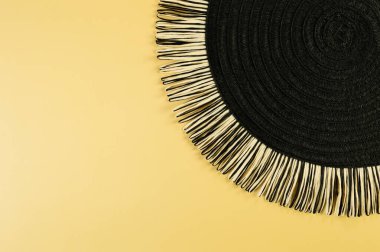 Sarı arkaplandaki siyah hasır masa örtüsünün üst görüntüsü. Saman yuvarlak tepsi, düz konum, kopyalama alanı. 