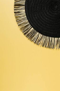 Sarı arkaplandaki siyah hasır masa örtüsünün üst görüntüsü. Saman yuvarlak tepsi, düz konum, kopyalama alanı. 
