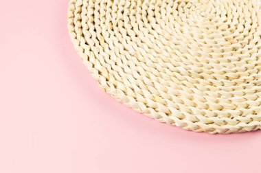 Pembe arkaplandaki kahverengi hasır masa örtüsünün üst görüntüsü. Saman yuvarlak tepsi, düz konum, kopyalama alanı.