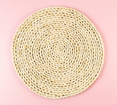 Pembe arkaplandaki kahverengi hasır masa örtüsünün üst görüntüsü. Saman yuvarlak tepsi, düz konum, kopyalama alanı.