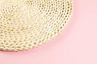 Pembe arkaplandaki kahverengi hasır masa örtüsünün üst görüntüsü. Saman yuvarlak tepsi, düz konum, kopyalama alanı.