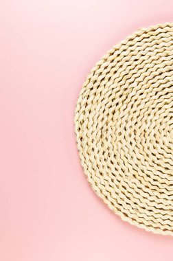 Pembe arkaplandaki kahverengi hasır masa örtüsünün üst görüntüsü. Saman yuvarlak tepsi, düz konum, kopyalama alanı.