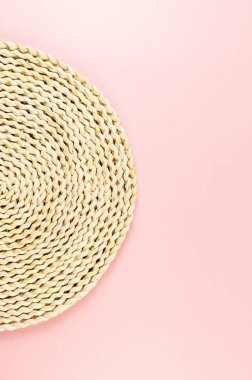 Pembe arkaplandaki kahverengi hasır masa örtüsünün üst görüntüsü. Saman yuvarlak tepsi, düz konum, kopyalama alanı.