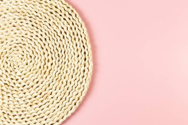Pembe arkaplandaki kahverengi hasır masa örtüsünün üst görüntüsü. Saman yuvarlak tepsi, düz konum, kopyalama alanı.