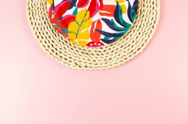 Kahverengi hasır masa paspasının üst görüntüsü, pembe arka planda renkli plaka. Saman tepsisi, egzotik bitki tabağı, yaz pikniği. Düz yat, boşluğu kopyala.