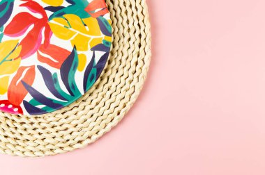 Kahverengi hasır masa paspasının üst görüntüsü, pembe arka planda renkli plaka. Saman tepsisi, egzotik bitki tabağı, yaz pikniği. Düz yat, boşluğu kopyala.