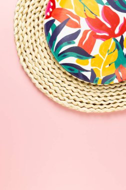 Kahverengi hasır masa paspasının üst görüntüsü, pembe arka planda renkli plaka. Saman tepsisi, egzotik bitki tabağı, yaz pikniği. Düz yat, boşluğu kopyala.