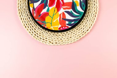 Kahverengi hasır masa paspası, siyah tepsi ve pembe arka planda renkli plaka. Saman tepsisi, egzotik bitki tabağı, yaz pikniği. Düz yat, boşluğu kopyala.