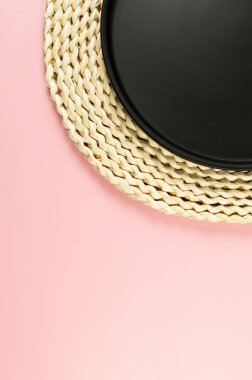 Kahverengi hasır masa paspası, pembe arka planda siyah plaka. Saman yuvarlak tepsi, düz konum, kopyalama alanı.