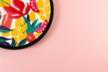 Pembe arka planda siyah tepsi ve renkli tabloların üst görüntüsü. Egzotik bitki plakası, yaz pikniği. Düz yat, boşluğu kopyala.
