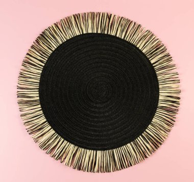 Pembe arkaplandaki siyah hasır masa örtüsünün üst görüntüsü. Saman yuvarlak tepsi, düz konum, kopyalama alanı.