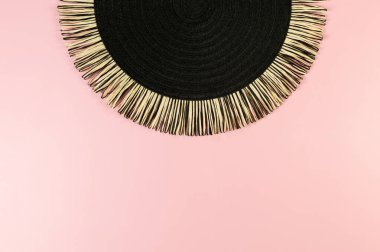 Pembe arkaplandaki siyah hasır masa örtüsünün üst görüntüsü. Saman yuvarlak tepsi, düz konum, kopyalama alanı.
