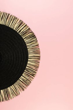 Pembe arkaplandaki siyah hasır masa örtüsünün üst görüntüsü. Saman yuvarlak tepsi, düz konum, kopyalama alanı.