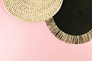 Kahverengi hasır masa paspası, siyah plaka, pembe arka planda siyah tepsi. Saman yuvarlak tepsi, düz konum, kopyalama alanı.