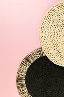 Kahverengi hasır masa paspası, siyah plaka, pembe arka planda siyah tepsi. Saman yuvarlak tepsi, düz konum, kopyalama alanı.