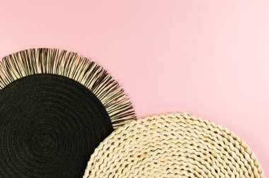 Kahverengi hasır masa paspası, siyah plaka, pembe arka planda siyah tepsi. Saman yuvarlak tepsi, düz konum, kopyalama alanı.