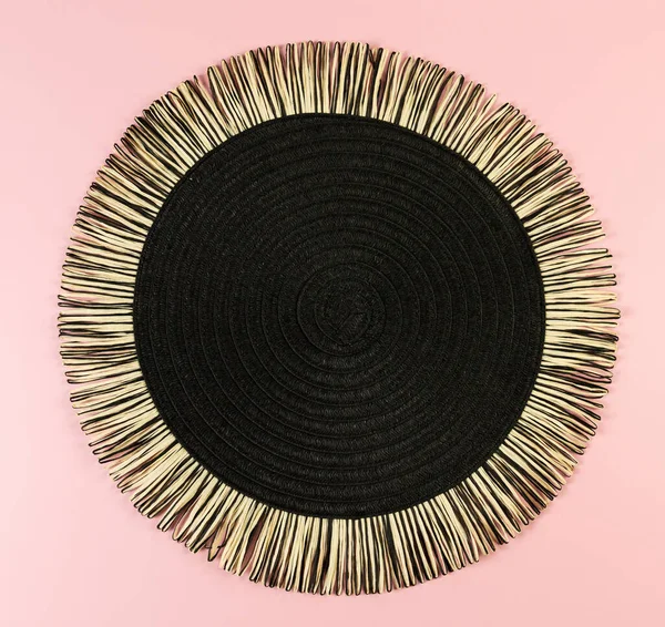 Pembe arkaplandaki siyah hasır masa örtüsünün üst görüntüsü. Saman yuvarlak tepsi, düz konum, kopyalama alanı.