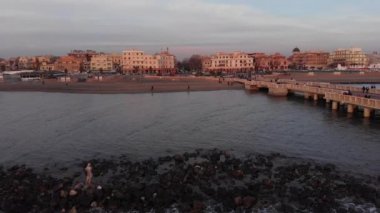 Ostia Lido sahilindeki gün batımı Roma hava manzarası uçurumun üzerinden deniz manzarası ve şehir merkezindeki Neptün heykelinin yıkılması ve Ravennati Meydanı 'nın manzarası ve yaya iskelesi turist ve sakinlerin dönüm noktası.