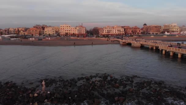 从海崖上俯瞰奥斯蒂亚 丽都海滩的日落 市中心天际线的海王星雕像的废墟 以及拉文纳提广场和平底锅的景观 可以看到一个游客和居民的地标码头 — 图库视频影像