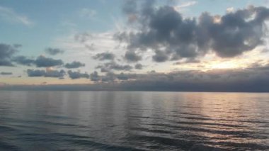 İpeksi denizin üzerinde harika bir gökyüzünde uçmak. Güneş batarken muhteşem hava manzarası. Duvar bulutları ve sirruslarla altın ufuk.