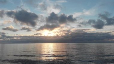 Güneş ışınlarının dalgalı sulara çarpmasıyla gün batımında inanılmaz renkli gökyüzü