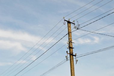 Renkli arka planda kablo olan elektrik direği yakın plan. Görüntü, elektrik direğinden ve gökyüzünün altındaki kablodan oluşuyor. Konut binaları için elektrik direğindeki hat kablosu.