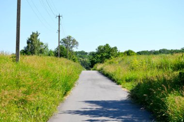 Renkli arka planda, kırsal alanda güzel boş asfalt yol. Fotoğrafçılık, kırsal kesimden geçen yeni boş asfalt yolu içeriyor. Yeşillik kırsalında hız aracı için boş asfalt yol