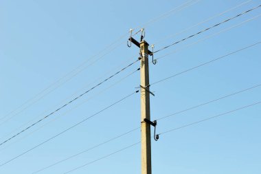 Renkli arka planda kablo olan elektrik direği yakın plan. Görüntü, elektrik direğinden ve gökyüzünün altındaki kablodan oluşuyor. Konut binaları için elektrik direğindeki hat kablosu.