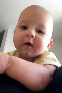 Renkli fotoğraf için poz veren çocuk yüzlü güzel bir oğlan. Cadre, çocuk görünümlü bir erkek bebekten, beyaz bir yüz ifadesinden oluşuyor. Sağlıklı erkek bebek, çocuk yüzü. İyi bir atış için rahatlıyor..