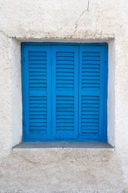 Güzel, canlı, mavi kepenkli bir pencere desenli bir kırsal duvar tasarımına eşsiz bir karakter ekler.