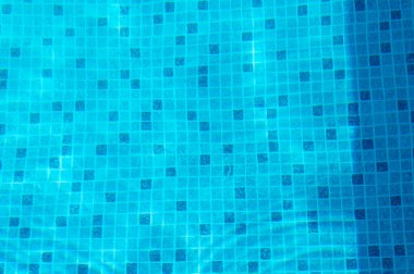 Yüzme havuzunun canlı mavi yüzeyi güzel ve çarpıcı mozaik desenler sergiliyor.