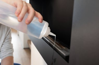 Bir adam siyah bir biyolojik şömineye biyoetanol döker, temiz, çevre dostu bir ateş yaratır..