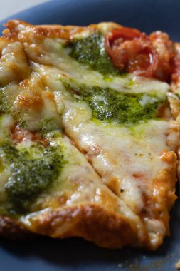 Seramik mavi tabak üzerine yakın rustik pizza porsiyonu, kekik ve bitki serpme, kaynayan peynir cepleri ve zeytinyağı çiselemesi, samimi karamsar ışıklandırma.,