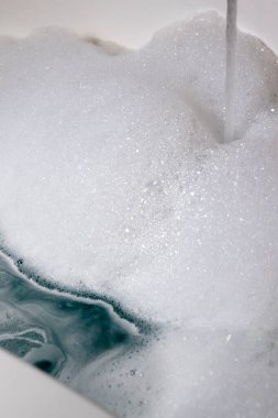 Mutfak lavabosundaki suyu kaplayan köpüklü sabun köpükleri bulaşıkları ve ev temizliği görevleri için hazır..